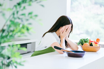 キッチンで悩む女性（泣く）
