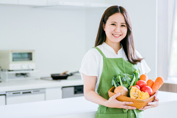 キッチンで野菜を持つ女性
