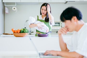 テレワークする男性と赤ちゃんと抱く女性
