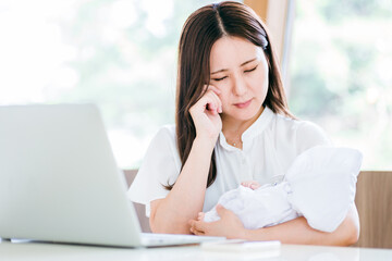 赤ちゃんと仕事で悩む女性

