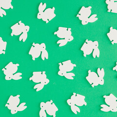 Naklejka premium Creative pattern made of white rabbits on a green background. Minimal flat lay concept. Easter inspiration.