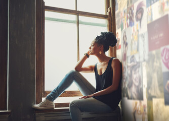 Fototapeta premium Enjoying the view. Shot of an attractive young woman sitting by the window.