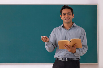 School teacher teaching in front of blackboard in classroom