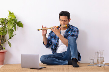 Young music teacher playing flute during online class in living room © IndiaPix