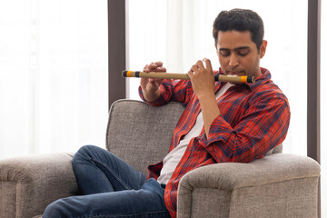 Portrait of a young musician playing flute in living room © IndiaPix