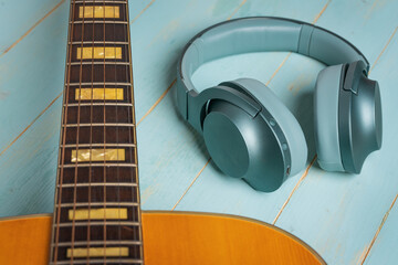 Beautiful acoustic guitar and green headphones on wooden background, closeup