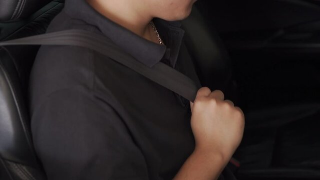 The driver did not know how to fasten the seat belt in the car. side view A young Asian man clicks his seat belt before driving. mindful driving concept
