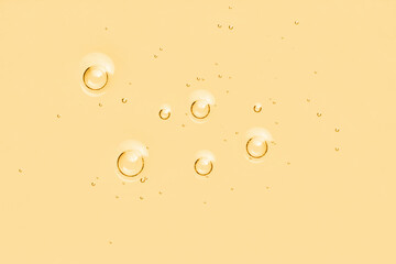 Yellow oil toner serum background. Skincare liquid surface with bubbles. Abstract cosmetic product...