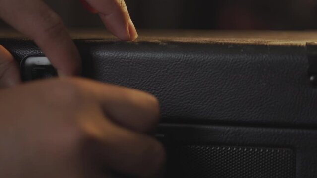 Turn on the vintage suitcase turntable turntable turn on. Put the record into the turntable. Close up. 4K resolution.
