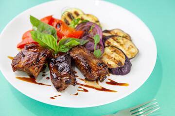 Grilled meat and vegetables. Zucchini, peppers, red onions and basil. Fried pork medallions. Food on a white plate in a restaurant