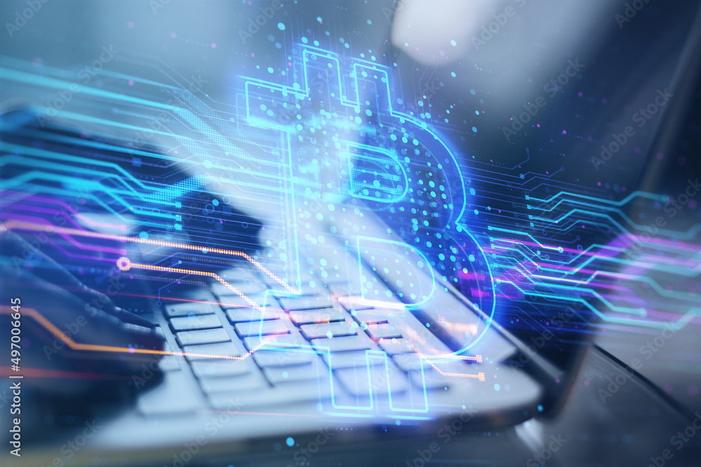 Poster close up of hands using laptop keyboard with creative blue bitcoin hologram on blurry office interio