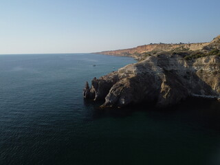 Aerial view from above on calm azure sea and volcanic rocky shores. Small waves on water surface in motion blur. Nature summer ocean sea beach background. Nobody. Holiday, vacation and travel concept