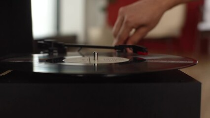 Close-up hands of unrecognizable man adjusting head old record player and vinyl discs at home. Music lover listening to classical music. Closeup of turning on turntable and placing needle on record.