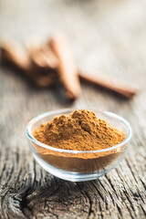 Dry cinnamon powder in bowl on wooden table. Cinnamon spice.