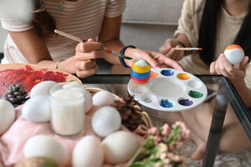Child and mother hand painting Easter egg with paintbrush. Easter holidays and people concept.