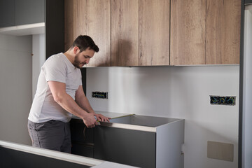 Young latin man using measuring tape before placing countertops on modern kitchen.