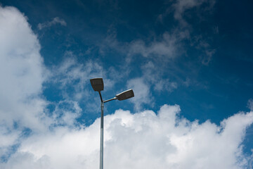 Street lighting pole with LED lights against blue sky with white clouds