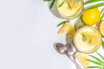 Lemon panna cotta dessert with fresh lemon wedges and sage leaves. Yellow citrus fruit panna cotta...