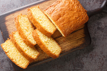 Tasty Madeira sponge cake closeup served on a wooden cutting board on the concrete table. Horizontal top view from  above