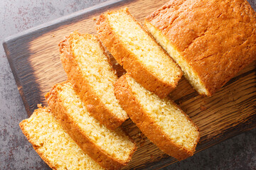 Madeira loaf cake closeup served on a wooden cutting board on the table. Horizontal top view from  above