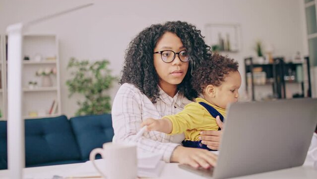 Working mom having online video call with a baby on her lap, work-life balance