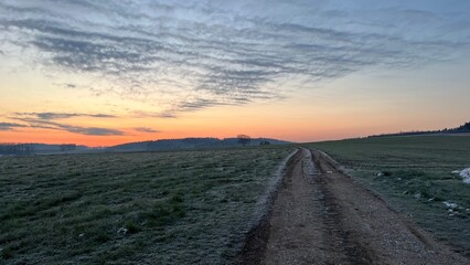 Ein wunderschönes Landschaftsbild in den Farben eines Frühlingsmorgen. Morgenfrost und ein orangefarbener Himmel lassen es fast surreal wirken.