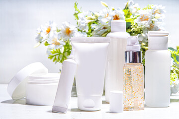 Fototapeta na wymiar Foraged and wild-harvested beauty, Cosmetic skincare products on white background with wild grown flowers. Set white jars, tubes, droppers, bottles. Spa, daily organic natural skin care routine
