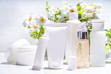 Foraged and wild-harvested beauty, Cosmetic skincare products on white background with wild grown flowers. Set white jars, tubes, droppers, bottles. Spa, daily organic natural skin care routine