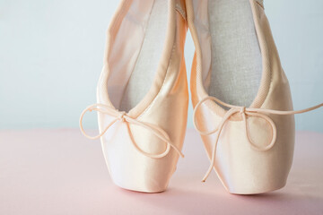 Pink ballet pointe shoes on a light background. Side view, space for text.