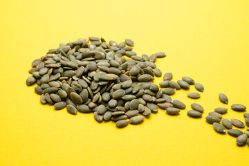 Pumpkin seed on a yellow background close-up.
