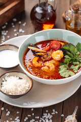 Bowl of thai seafood tom yam soup with rice on the wooden background