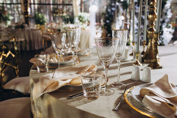 Wedding. Banquet. Decor. Festive tables on the terrace in the forest are decorated with compositions of white flowers and greenery, there are candles, plates with numbers, plates and glasses