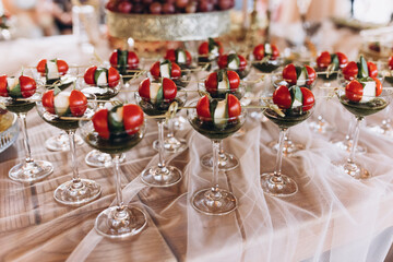 Wedding. buffet. Catering. On the banquet table are glasses with appetizers of cherry tomatoes, mozzarella and pesto