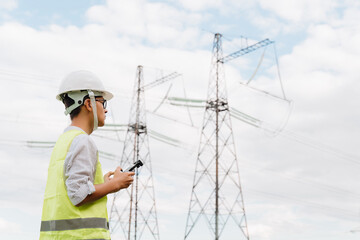 A young Engineer examines the high-voltage tower with a drone.