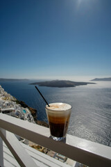 An iced coffee, also known as Freddo Cappuccino,  overlooking the aegean sea and the famous village...