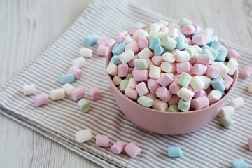 Obraz premium Rainbow Fruity Mini Marshmallows in a Pink Bowl, side view. Copy space.