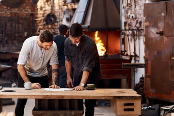 Obraz na płótnie Canvas Were working on a huge project together. Cropped shot of two handsome young businessmen working together inside their workshop.