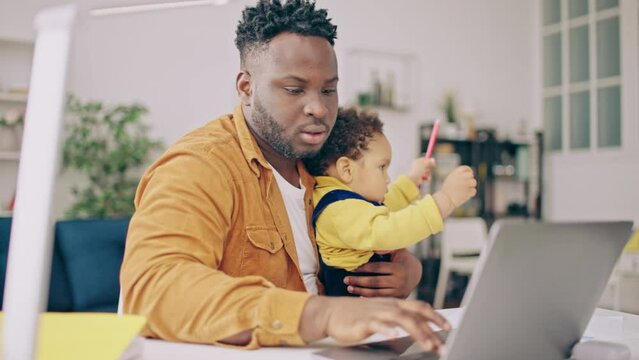 Busy young man working on laptop and taking care of infant son, parental leave