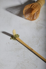 Word matcha made of powdered matcha green tea and bamboo spoon on light textured background. Copy space