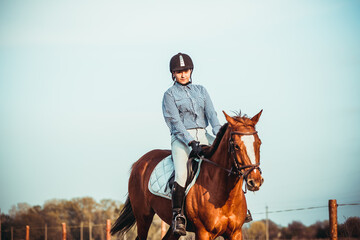 Young woman athlete rides a horse. Jumping training in the spring in the field.