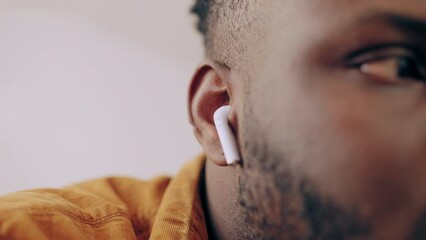 African American man putting wireless earbuds in his ears, enjoying new device