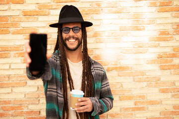 Handsome guy drinking coffee while walking in the street. Modern fashion man using the phone.