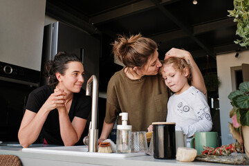 Happy lesbian couple with their adopted child doing housework together