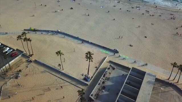 Venice beach California Drone shot moving forward  panning up on beach  front over basketball courts with sand and water