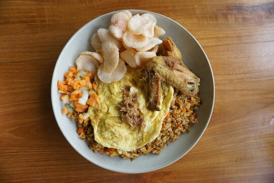 proper breakfast menu. a plate of fried rice topped with fried chicken, omelette and crackers.