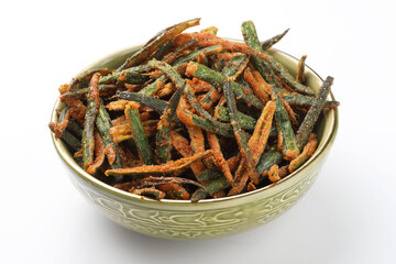 Bhindi kurkure or crunchy okra or ladies' fingers, a Rajasthani traditional dish served in a ceramic bowl on wooden board along with ingredient for the recipe