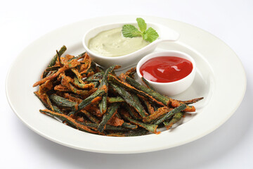 Bhindi kurkure or crunchy okra or ladies' fingers, a Rajasthani traditional dish served in a ceramic bowl on wooden board along with ingredient for the recipe