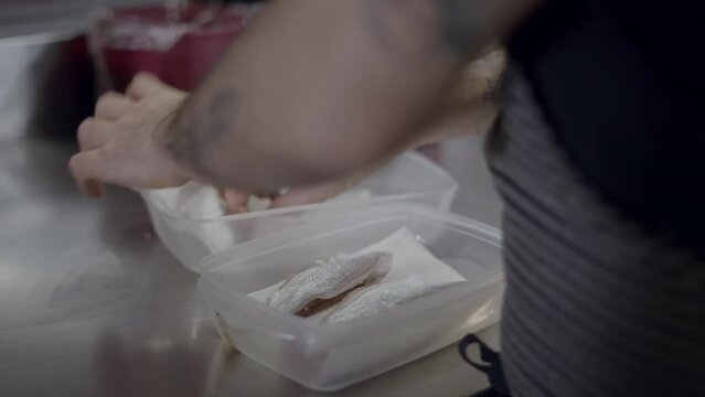 Close view of male chef&rsquo;s hands moving fish fillets between containers