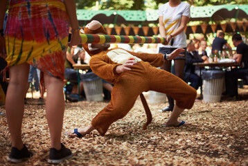 Monkeying around. A guy dressed in a monkey costume doing the limbo dance at a music festival. - obrazy, fototapety, plakaty