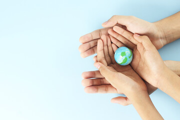 Happy earth day - Top view of two hands hold earth on blue background